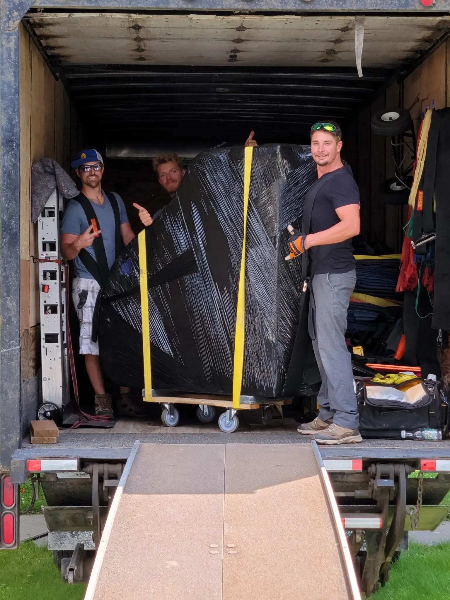 Three crew members giving a thumbs-up in the loaded moving truck