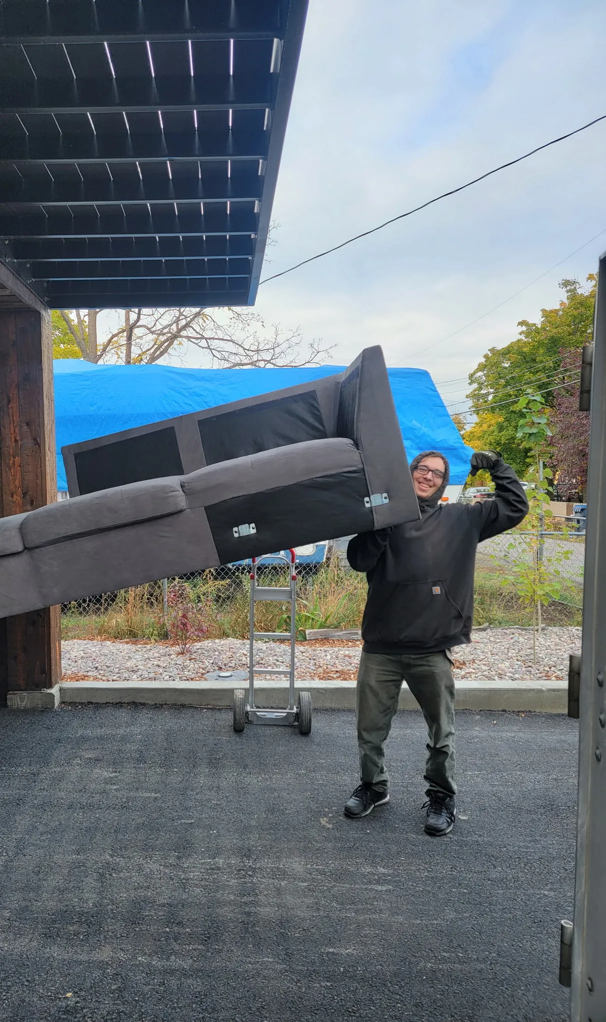 A Moving On Up crew member carrying a sofa over one shoulder outside a Missoula home