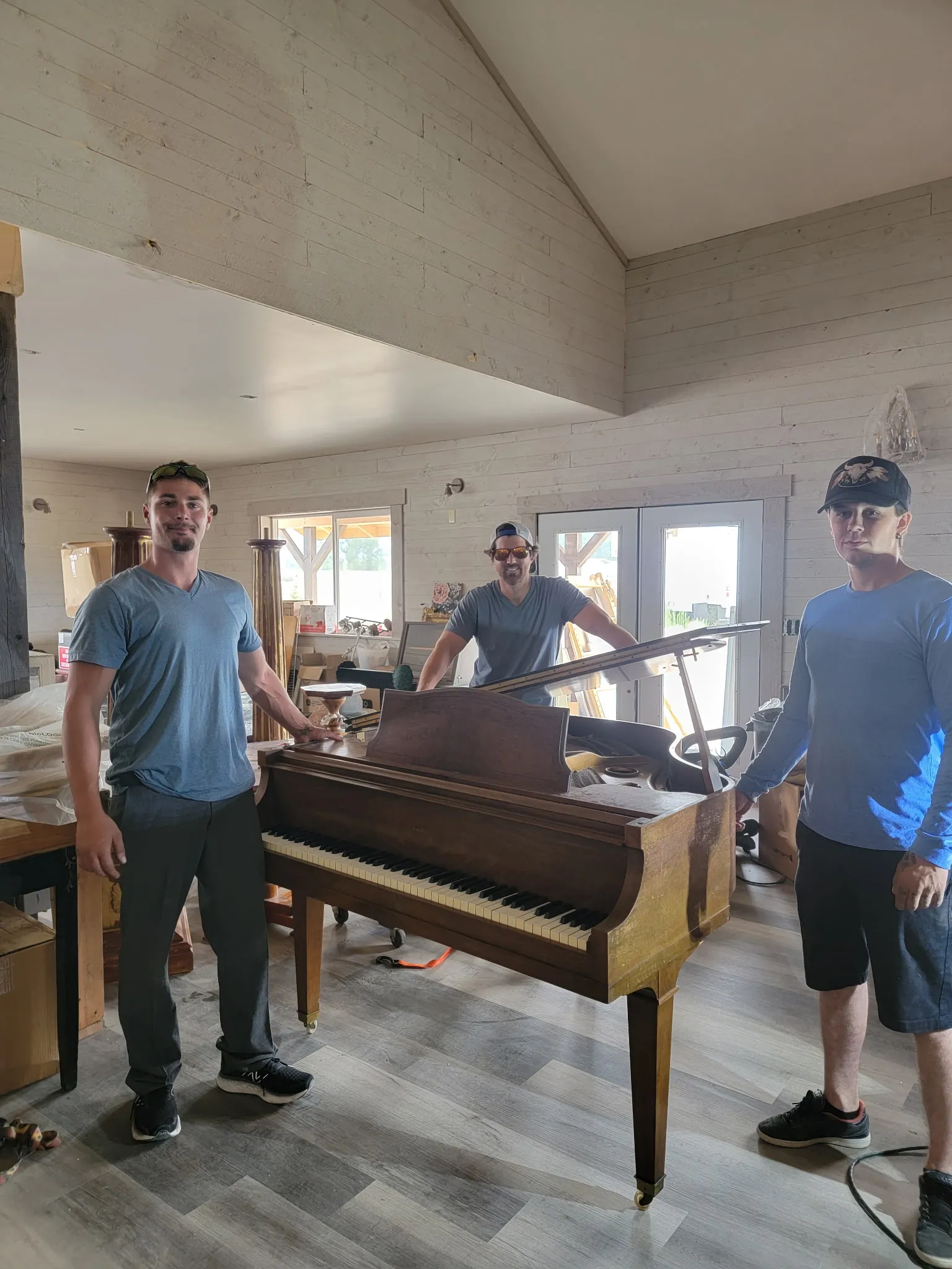 Crew carefully moving a grand piano in a bright Montana home